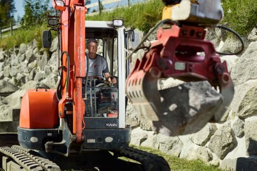 Rolf Behringer im Bagger hebt Steine