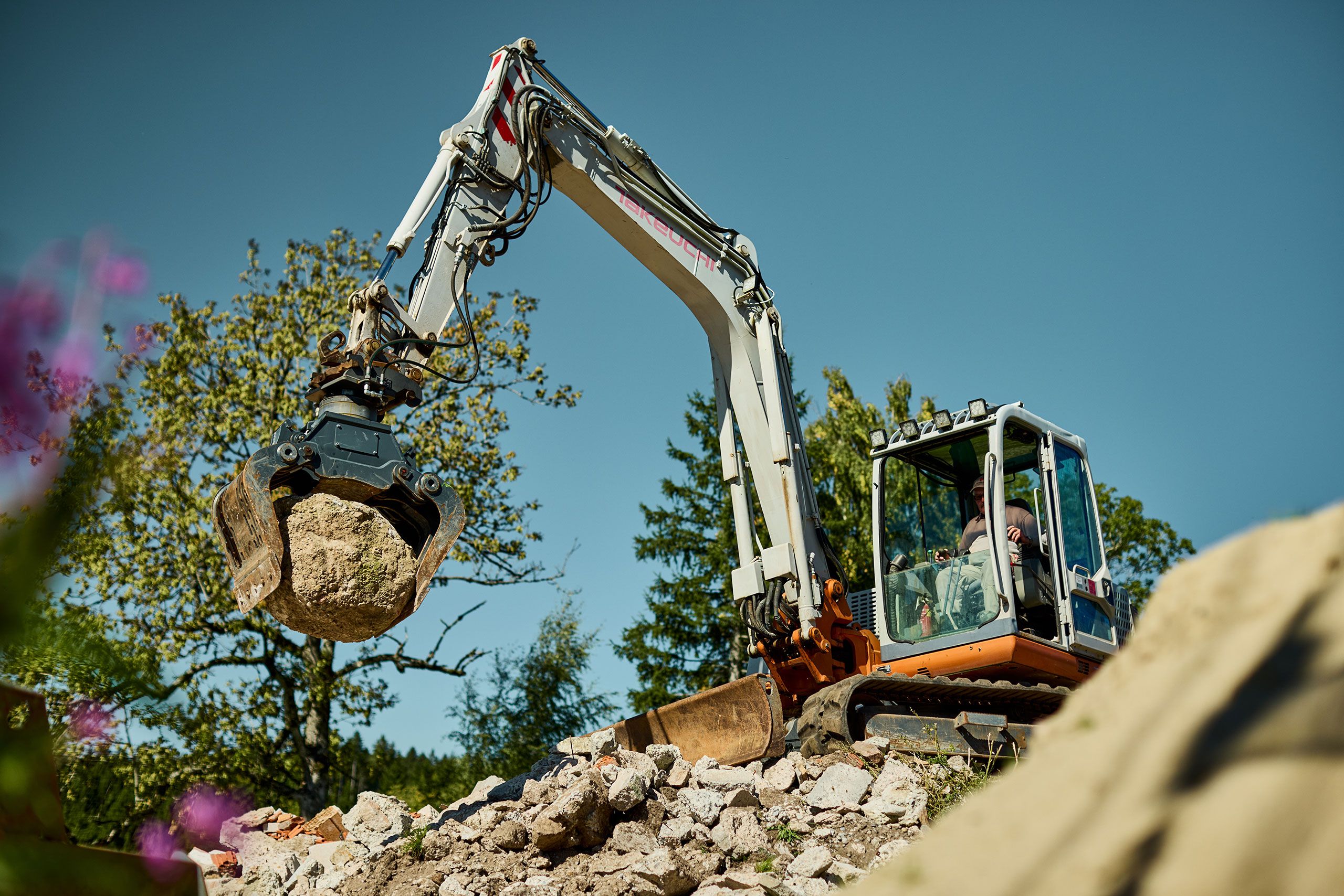 Mitarbeiter mit Bagger versetzt große Steine